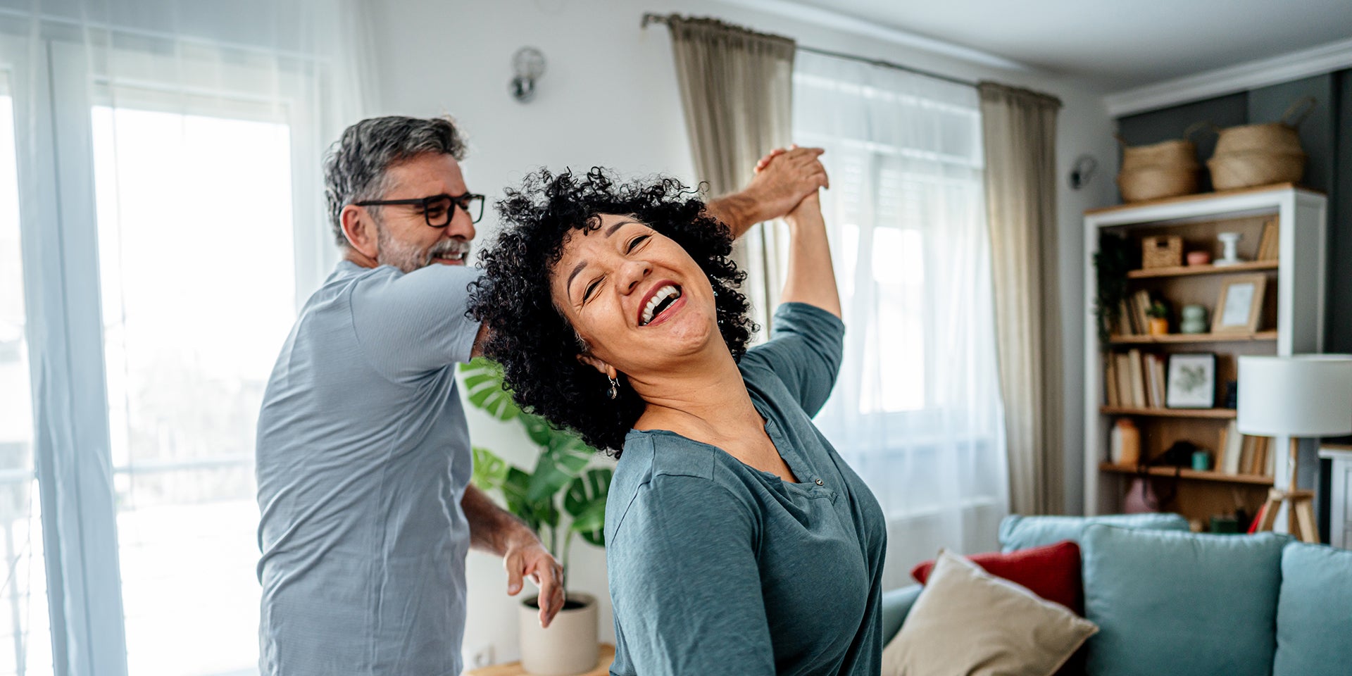 Man and woman smiling and dancing in their living room