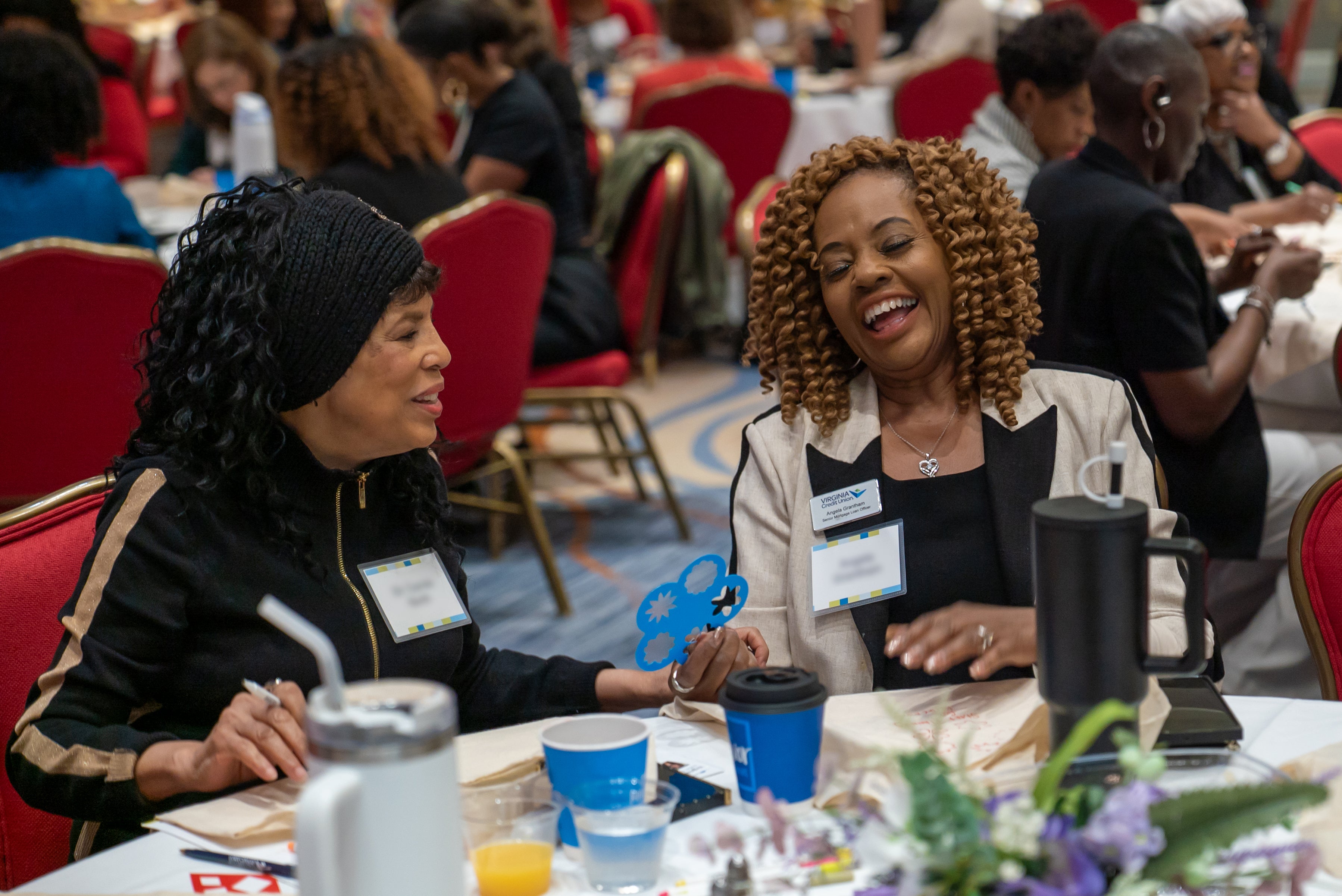 Two participants laughing and smiling while participating in activities at the Financial Success for Women Summit