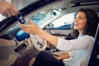 A woman sitting in the driver's seat of a new vehicle.