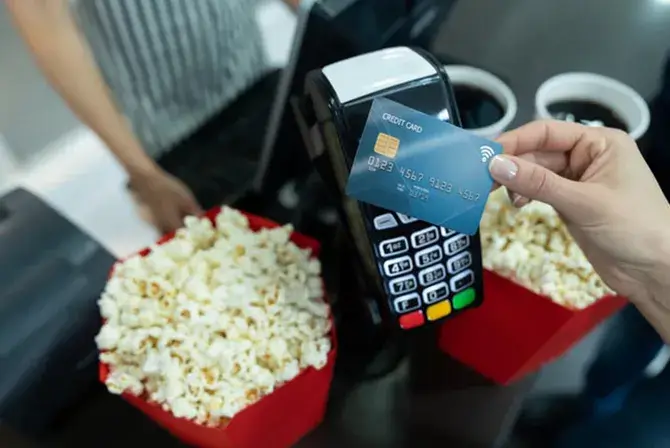 Individual uses credit card and tap to pay to purchase concession at the movies