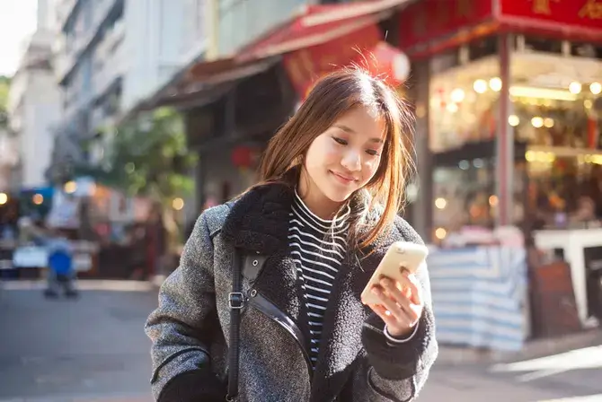 Teen girl walking on the street and looking at her mobile phone