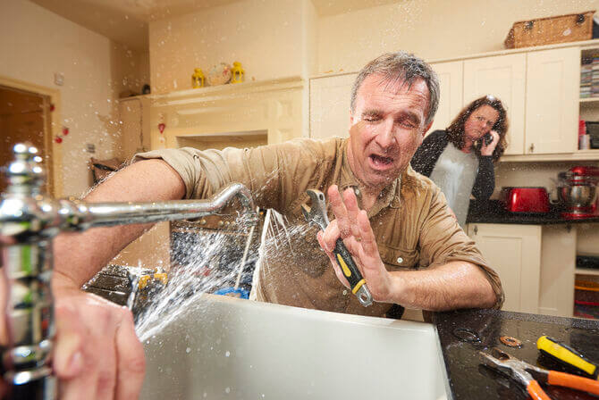man getting sprayed by broken faucet 