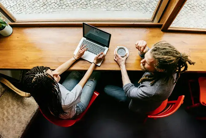 Man and woman sitting and talking in front of a laptop