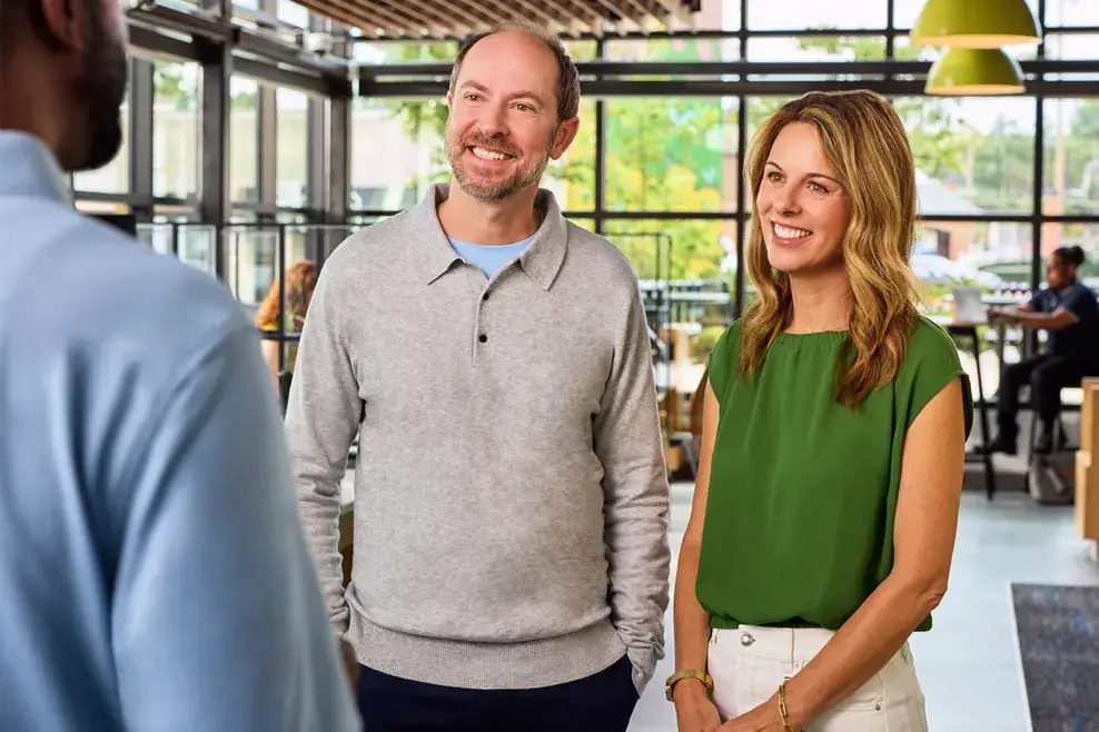 Smiling man and woman speak with a man inside a bright, modern storefront.