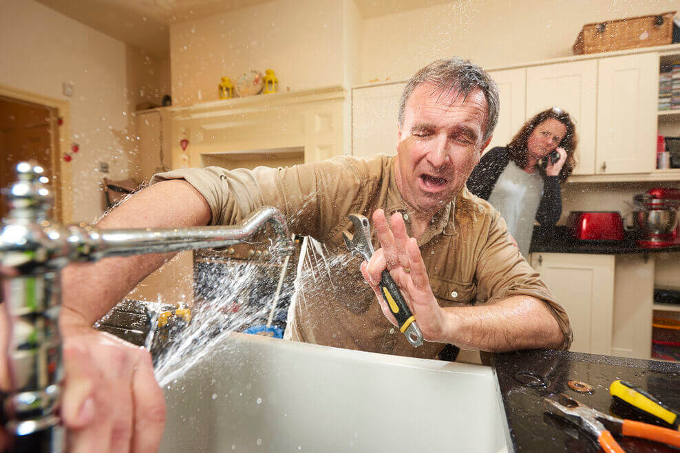 man getting sprayed by broken faucet 