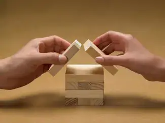 Two hands building a Jenga house.