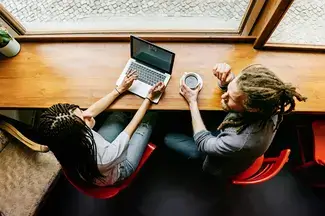 Man and woman sitting and talking in front of a laptop