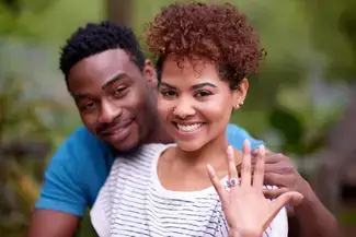A happy young couple showing off the engagement ring.