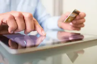 A person on an iPad typing in credit card information.
