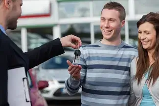 A young couple being handed a set of keys.