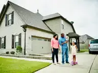 Parents standing with their two children on a driveway in front of their home