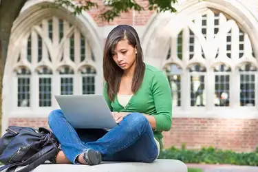 Student sitting on campus typing on the computer