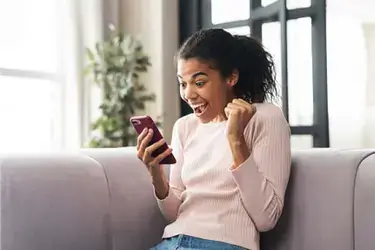 A woman looking at her phone and cheering