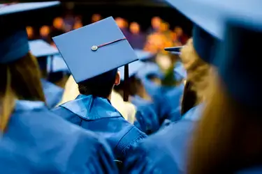 Graduates wearing blue caps and gowns while sitting at graduate ceremony
