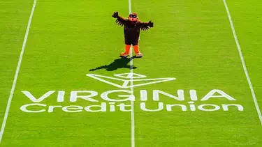 Virginia Tech mascot stands on field with Virginia Credit Union logo