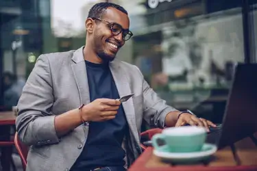 A smiling man at a cafe using his credit card online.