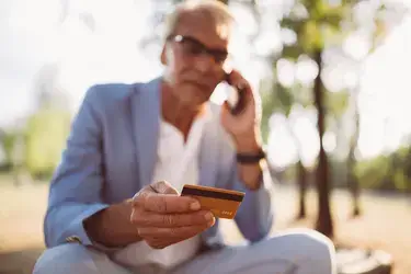 man holding credit card while talking on the phone