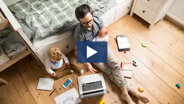 A father holding his baby while doing work