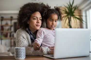 A woman with her young daughter staring at a laptop screen.