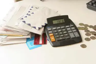 A calculator next to a stack of envelopes and some change.