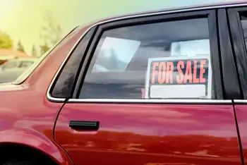 A vehicle window with a "For Sale" sign in the window.