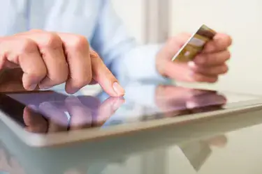 A person on an iPad typing in credit card information.