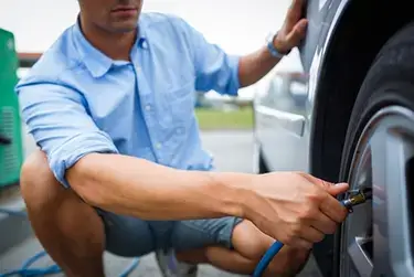 A man inflating his car tires with air.