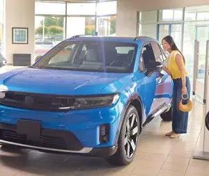 Woman looking inside of blue parked car at the dealership