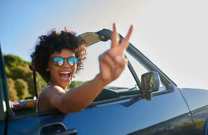 woman smiling with hand out of a car window