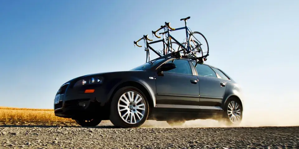 Car driving down dirt road while carrying bikes