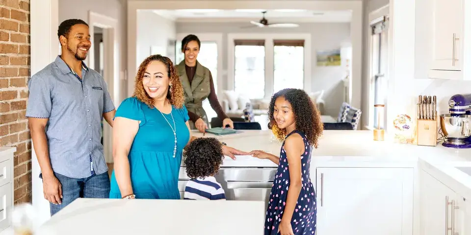 Family of 4 standing in kitchen at an open house tour
